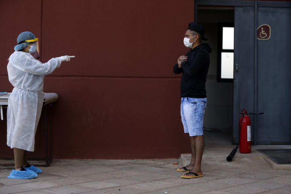 A youth in quarantine is interviewed by a member of the National Mechanism to Prevent Torture (MNPT), as the institution visits a sports facility that was turned into a government-run shelter where citizens returning home are required by law to quarantine for two weeks and pass two consecutive COVID-19 tests, as a preventive measure amid the COVID-19 pandemic near Ciudad del Este, Paraguay, Thursday, June 24, 2020. There are 15,000 Paraguayans still waiting to reenter the country in neighboring nations like Brazil and Argentina. (AP Photo/Jorge Saenz)