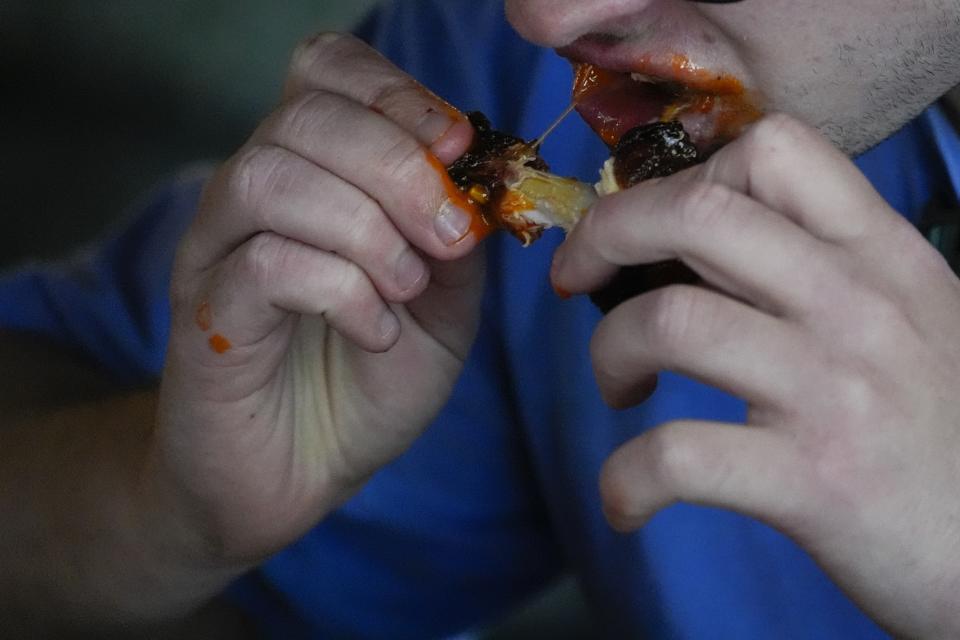 A man eats a chicken wing, Wednesday, June 12, 2024, at a barbecue restaurant in Cincinnati. Psychologists have known for years now that men tend to eat more meat than women, but a study of people around the world now reveals that that's true across cultures. (AP Photo/Joshua A. Bickel)