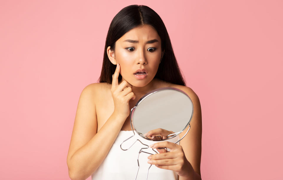 A woman looks shocked a she stares in the mirror