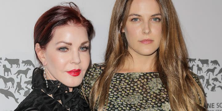 priscilla presley and riley keough on a red carpet where riley has her arm around her