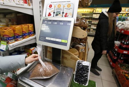 A woman weights a pack of buckwheat groats at a food market in Russia's Siberian city of Krasnoyarsk November 25, 2014. REUTERS/Ilya Naymushin