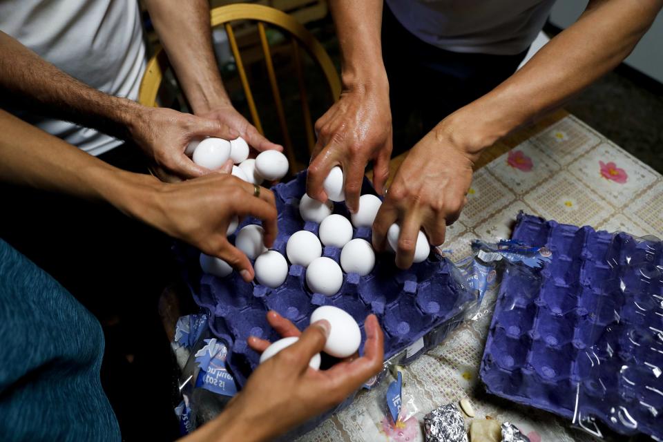 Migrants grab eggs as they cook a meal inside a shelter used mostly by Mexican and Central American migrants who are applying for asylum in the U.S., on the border in Tijuana, Mexico, Sunday, June 9, 2019. The mechanism that allows the U.S. to send migrants seeking asylum back to Mexico to await resolution of their process has been running in Tijuana since January. (AP Photo/Eduardo Verdugo)
