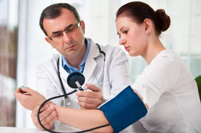 A male doctor checking the blood pressure of a young female patient