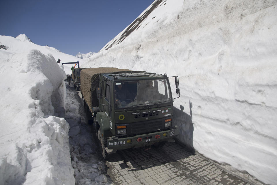 FILE - In this April 30, 2016, file photo, Indian army trucks carrying supplies for soldiers drive past walls of snow on the Zojila Pass, northeast of Srinagar, Indian controlled Kashmir. High in a rocky Himalayan mountain range, hundreds of people are working on an ambitious project to drill tunnels and construct bridges to connect the Kashmir Valley with Ladakh, a cold-desert region isolated half the year because of massive snowfall. The $932 million project’s last tunnel, about 14 kilometers (9 miles) long, will bypass the challenging Zojila pass and connect Sonamarg with Ladakh. Officials say it will be India’s longest and highest tunnel at 11,500 feet (3,485 meters). (AP Photo/Dar Yasin)