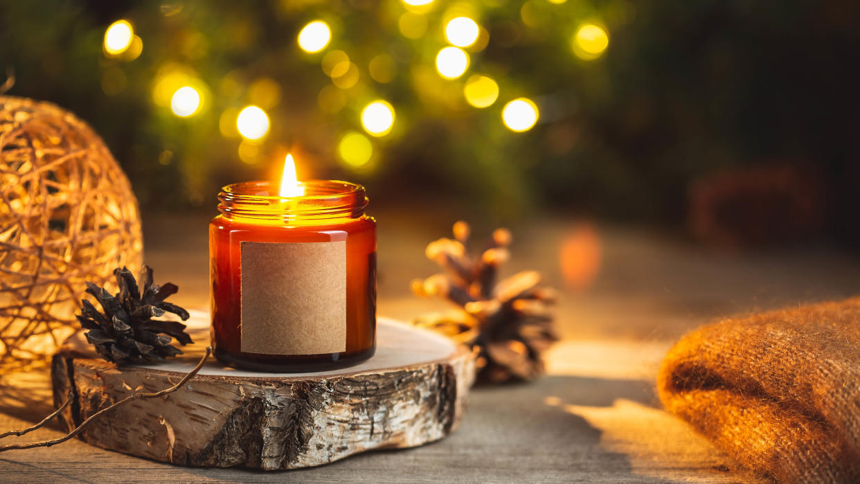  A scented candle in front of a Christmas tree. 