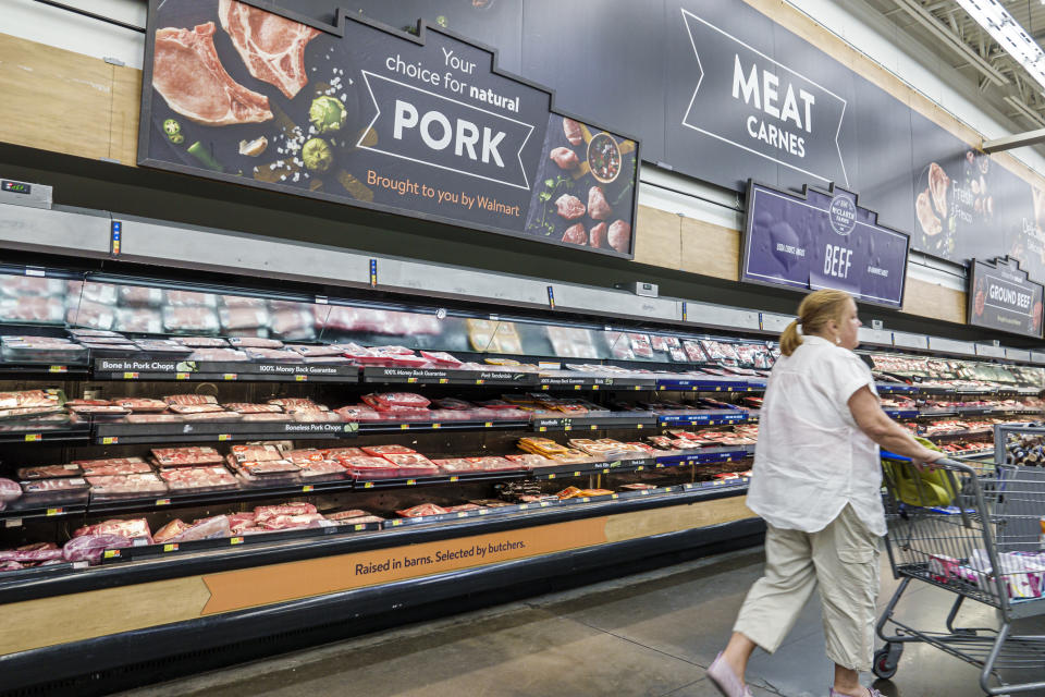 A woman pushes her cart through the refrigerated meat aisle at Walmart. 