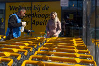 Raffat Altekrete, left, talks to school teacher Karina Zuidinga, as he is battling the coronavirus one shopping cart at a time he using a disinfecting spray outside a supermarket in Ter Apel, north-eastern Netherlands, Tuesday, March 31, 2020. The Iraqi migrant, armed with latex gloves, a cleaning rag and a spray bottle of disinfectant is also aiming to express his gratitude and win hearts in a small Dutch community that hosts the Netherlands' biggest asylum seeker center. (AP Photo/Peter Dejong)