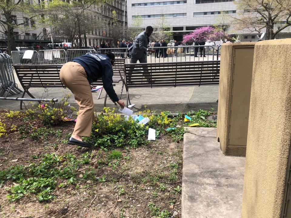 Law enforcement officials are seen picking up pamphlets off the ground moments after a person reportedly self-immolated outside the Manhattan Criminal Court in New York on April 19, 2024.