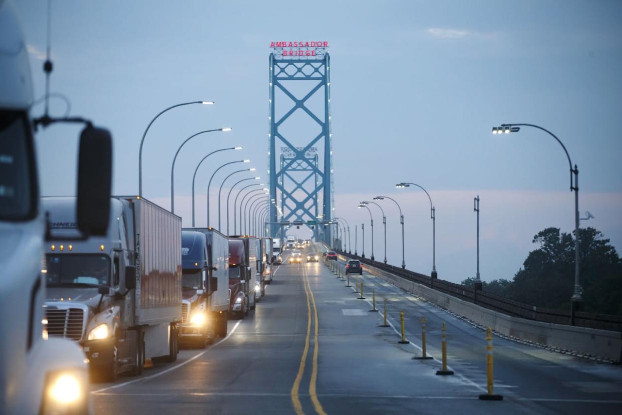 Commercial trucks and passenger vehicles drive across Ambassador Bridge on the Canada-U.S. border. (Cole Burston/Bloomberg - image credit)