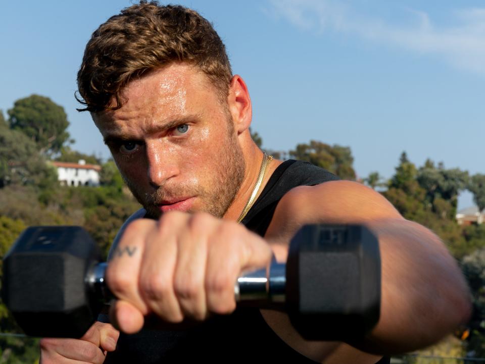 Olympian Gus Kenworthy working out with dumbbell weights
