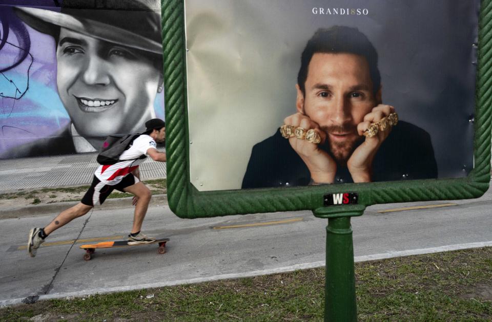 A man skates near an advertising billboard with a portrait of the soccer legend Lionel Messi, in front, and behind a mural with the image of the legendary tango singer Carlos Gardel, in Buenos Aires, Argentina, Monday, Nov. 6, 2023. (AP Photo/Rodrigo Abd)