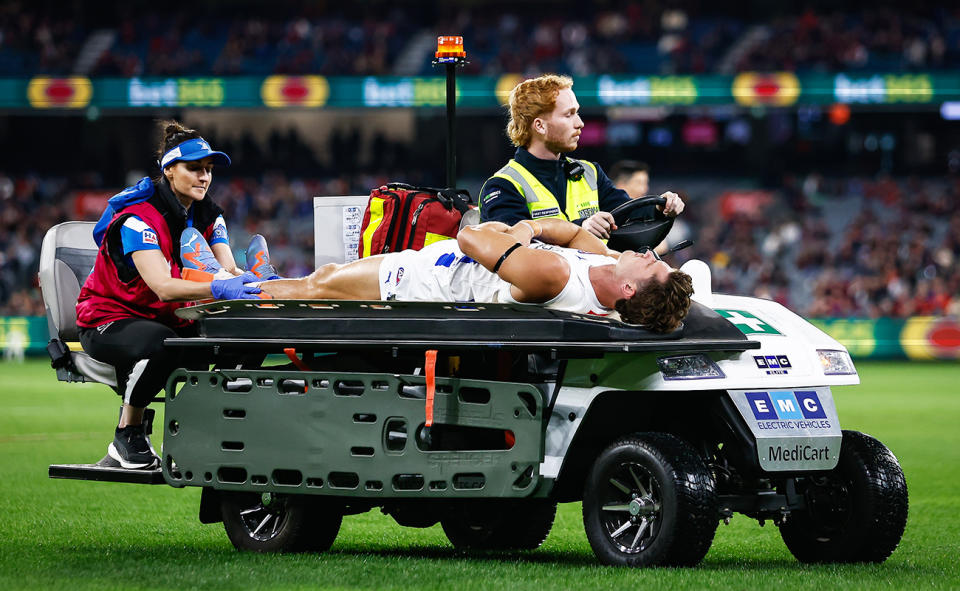 Charlie Comben, pictured here being taken off the field on a medicab during North Melbourne's clash with Melbourne.