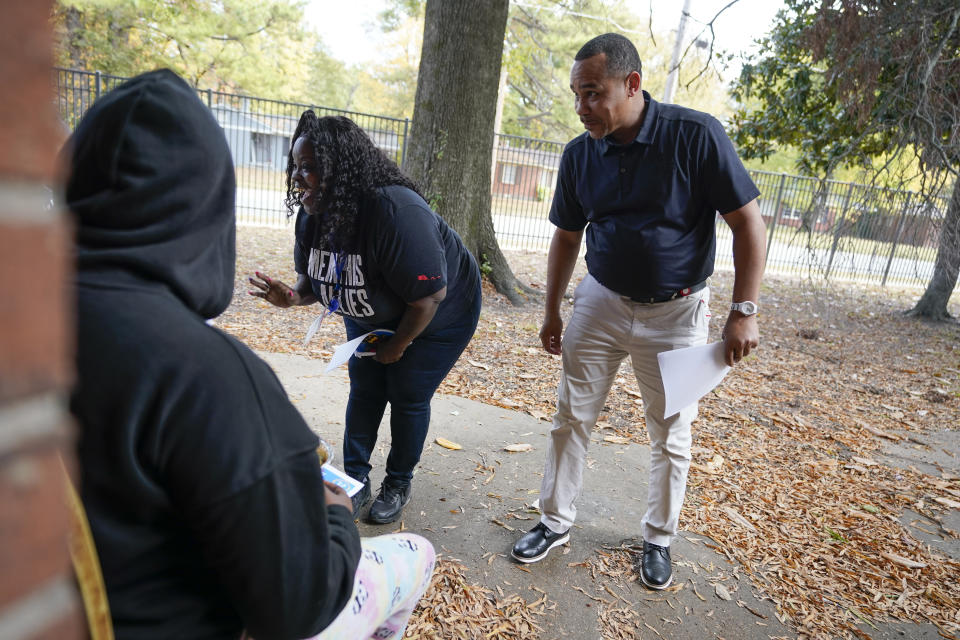 Tony Matthews, right, and Florence Brooks, center, hand out fliers in an apartment complex about an upcoming event sponsored by anti gun violence group Memphis Allies on Oct. 24, 2022, in Memphis, Tenn. Both Matthews and Brooks are life coaches with the organization. (AP Photo/Mark Humphrey)