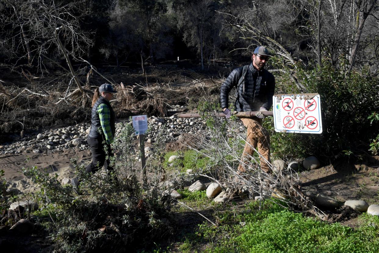 Melissa Baffa and Dan Hulst of the Ventura Land Trust retrieve a sign at Big Rock Preserve along the Ventura River on Jan. 19. Recent storms caused the Ventura River to swell and damage large areas of the property.