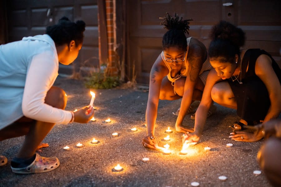 Sandriana McBroom, right, and Makhiya Mcbroom, center, light candles that spell out “RIP Kiya” at a vigil held Friday, Aug. 25, 2023, in Columbus, Ohio, for their friend, Ta’Kiya Young, 21, who was shot and killed a day earlier by Blendon Township police outside an Ohio supermarket. (Courtney Hergesheimer/The Columbus Dispatch via AP)