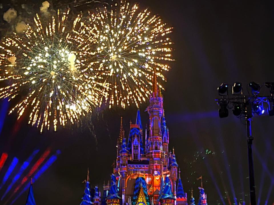 fireworks over a lit up castle at disney world