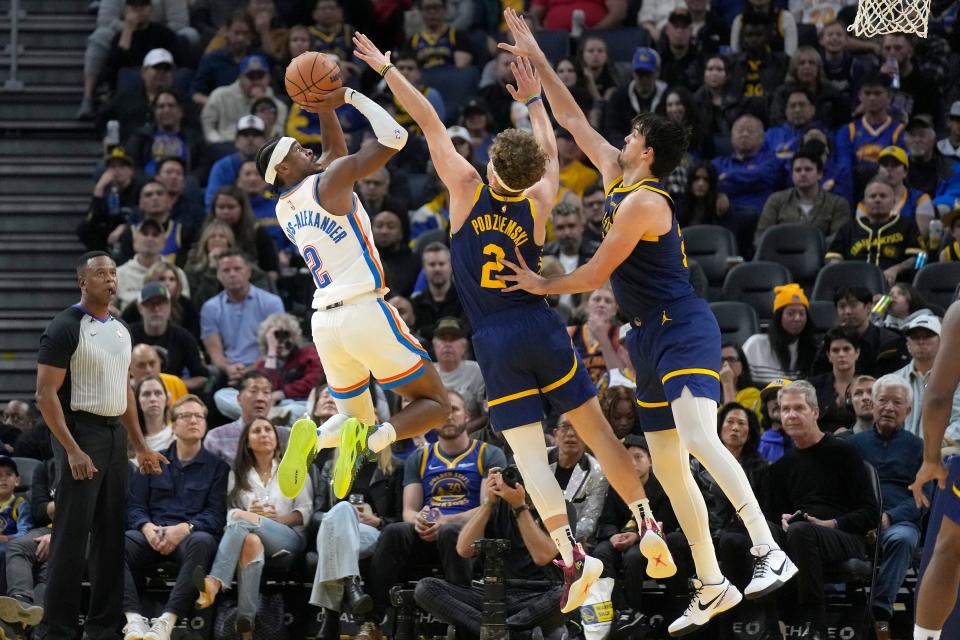 Thunder guard Shai Gilgeous-Alexander, left, scores against Warriors guard Brandin Podziemski, middle, and forward Dario Saric during the second half Saturday in San Francisco.