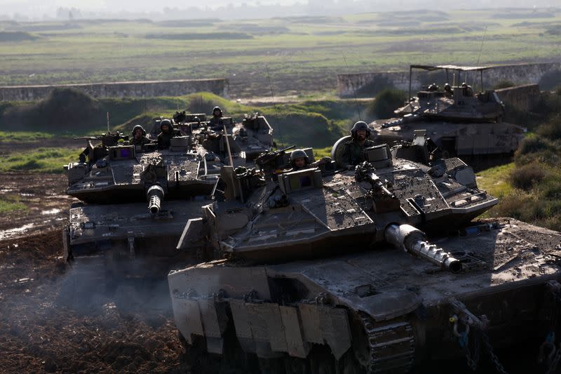 Israeli soldiers ride tanks while moving out of the Gaza Strip, as seen from southern Israel