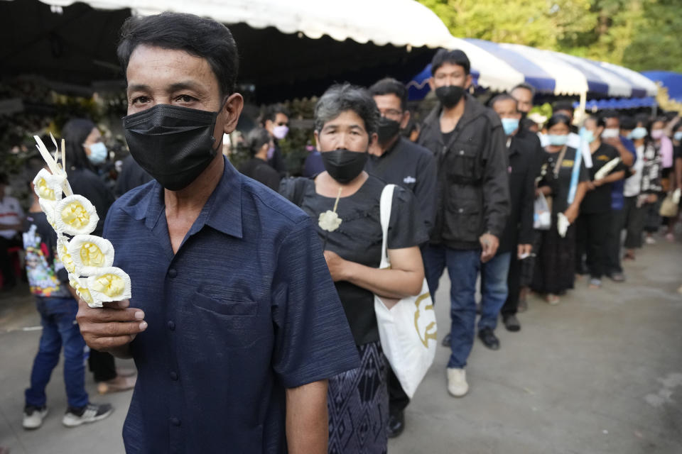 People line up to pay their respects to the mass attack victims before their cremation at Wat Rat Samakee temple in Uthai Sawan, northeastern Thailand, Tuesday, Oct. 11, 2022. A former police officer burst into a day care center in northeastern Thailand on Thursday, killing dozens of preschoolers and teachers before shooting more people as he fled. (AP Photo/Sakchai Lalit)