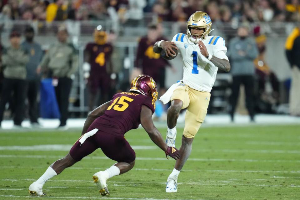 UCLA's Dorian Thompson-Robinson leaps by Arizona State's Khoury Bethley.