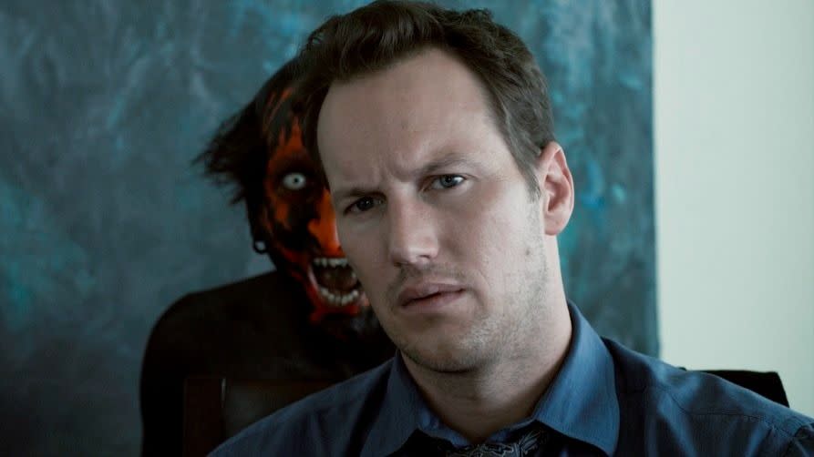 a redfaced demon stands behind an unsuspecting man in a scene from insidious, a good housekeeping pick for best halloween movies