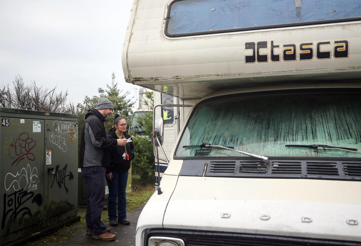 With Point In Time Count questionnaires in hand, HEART Program Coordinator Jarrod Moran talks with occupants standing inside the doorway of an RV who were staying on Charleston Beach Road in Bremerton on Friday, Jan. 26, 2024,