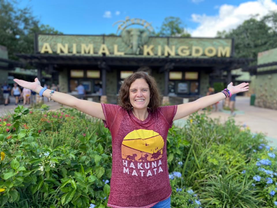 kari posing with her arms spread wide in front of the entrance to animal kingdom