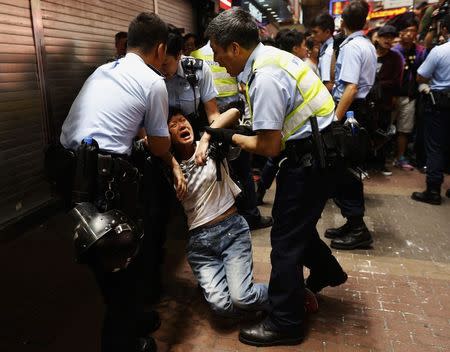 A passerby frightened by police action is helped on a pavement at Mongkok shopping district in Hong Kong November 26, 2014. REUTERS/Bobby Yip