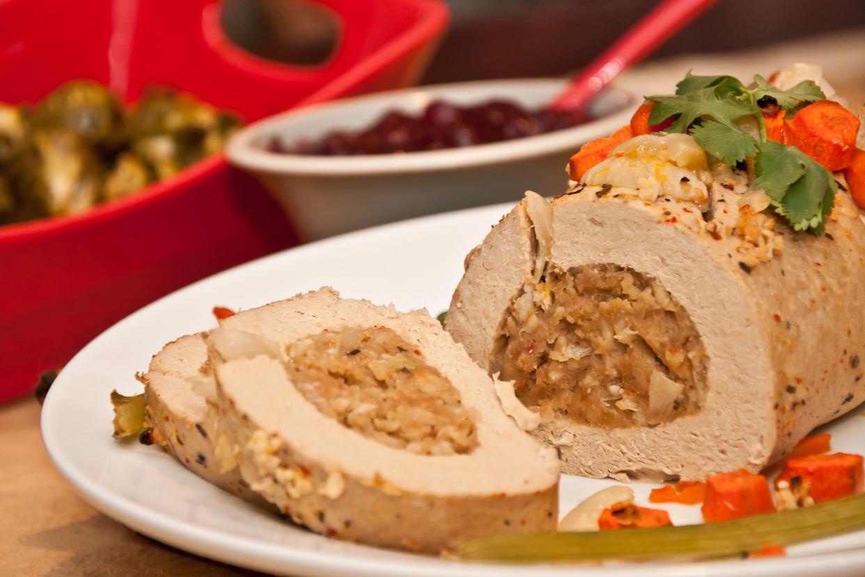 Vegan 'celebration roast' on a white plate with a blurred background of ingredients