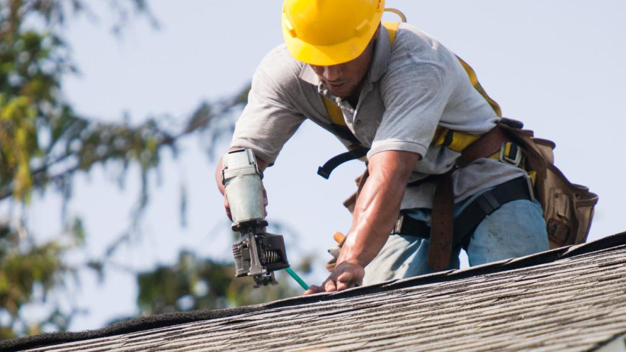 A roofer installing shingles