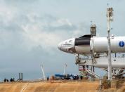 Crews work on the SpaceX Crew Dragon, attached to a Falcon 9 booster rocket, as it sits horizontal on Pad39A