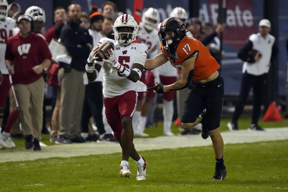 Wisconsin cornerback Cedrick Dort Jr. intercepts the football in front of Oklahoma State wide receiver John Paul Richardson (17) during the second half of the Guaranteed Rate Bowl NCAA college football game Tuesday, Dec. 27, 2022, in Phoenix. Wisconsin 24-17. (AP Photo/Rick Scuteri)