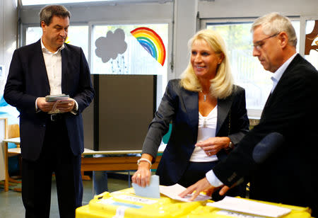 Markus Soeder, top candidate of the Christian Social Union Party (CSU), watches as his wife Karin Baumueller casts her vote, next to the electoral assistant, for the Bavarian state election in Nuremberg, Germany, October 14, 2018. REUTERS/Wolfgang Rattay