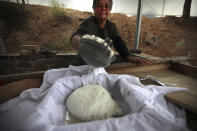 In this photo taken Wednesday Dec. 11, 2019, Aphrodite Philippou, 73, takes out cheese from a saucepan as she makes Cyprus' halloumi cheese at a farm in Kampia village near Nicosia, Cyprus. Cyprus' halloumi cheese, with a tradition dating back some five centuries, is the island nation's leading export. It's goat and sheep milk content makes it a hit with health-conscious cheese lovers in Europe and beyond. It's added appeal is that unlike other cheeses, it doesn't melt when heated up. (AP Photo/Petros Karadjias)