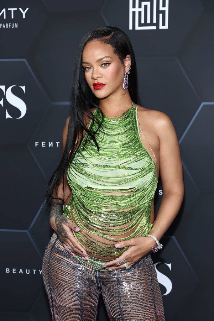 Rihanna berce son baby bump alors qu'elle pose sur le tapis rouge dans un haut à sequins à franges