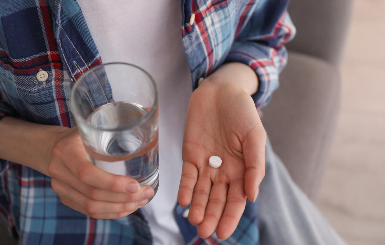 A woman holds an abortion pill in one hand, a glass of water in the other hand. Self-managed abortions, done with prescription medications, can be safe and effective, according to doctors and studies.