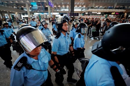 Riot police walk inside the airport as anti-extradition bill protesters gather outside, in Hong Kong