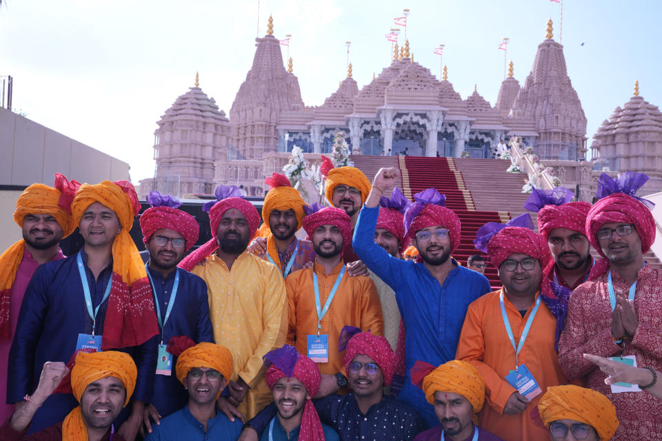 A group of devotees cheer as they pose for photographs before the opening of the first stone-built Hindu temple in the Middle East, in Abu Mureikha, 40 kilometers (25 miles) northeast of Abu Dhabi, United Arab Emirates, Wednesday, Feb. 14, 2024. (AP Photo/Kamran Jebreili)