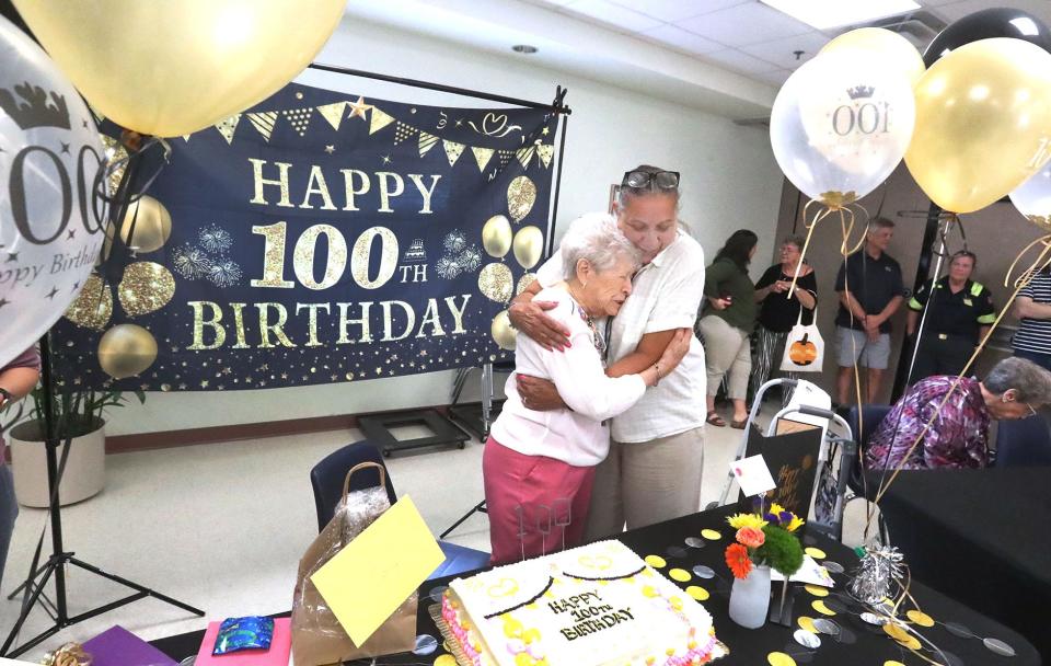 Elizabeth Parisi gets a hug from Evelyn Barrios, a Council on Aging nutrition coordinator, on her 100th birthday, Wednesday, Oct. 11, 2023, during a celebration at the Adult Activity Center.