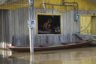 A resident crouches on a raised floor set up inside a home to stay above floodwaters in Anama, Amazonas state, Brazil, Thursday, May 13, 2021. (AP Photo/Edmar Barros)