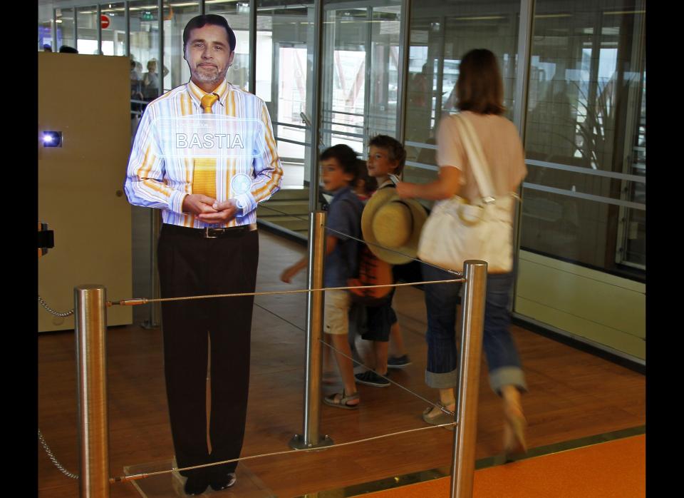 An airport experimenting "virtual" boarding agent, left, is displayed at Paris' Orly airport, on the southern outskirts of Paris, Thursday, Aug. 18, 2011. The pilot project began last month, and has so far been met with a mix of amusement and surprise by travellers, who frequently try to touch and speak with the strikingly life-like video images that greet them and direct them to their boarding gate.