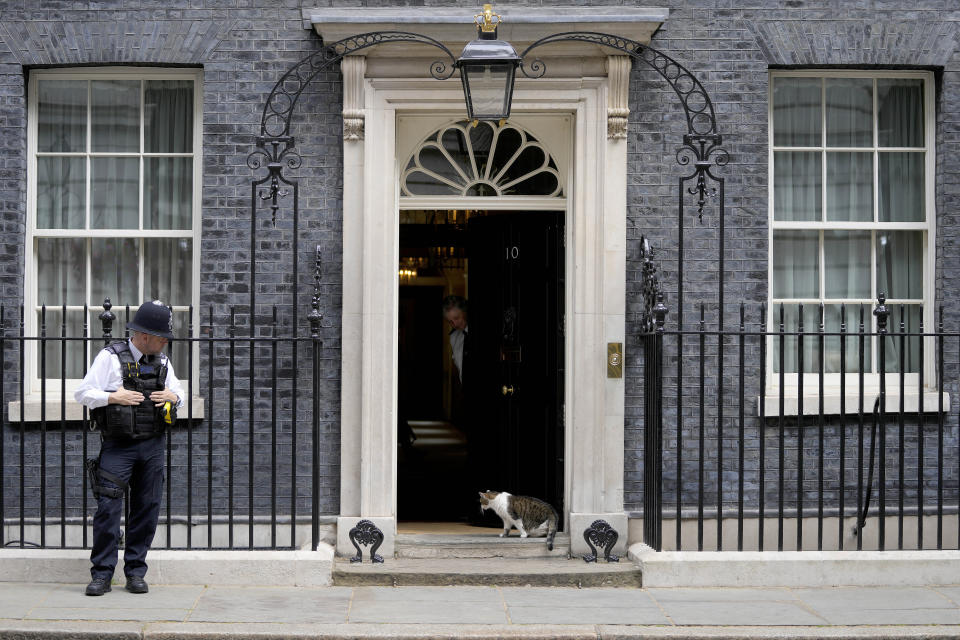 A police officer guards 10 Downing Street as Larry the Cat, Britain's Chief Mouser to the Cabinet Office, walks in, in London, Friday, June 24, 2022. British Prime Minister Boris Johnson suffered a double blow as voters rejected his Conservative Party in two special elections dominated by questions about his leadership and ethics. He was further wounded when the party's chairman quit after the results came out early Friday, saying Conservatives “cannot carry on with business as usual.” (AP Photo/Frank Augstein)