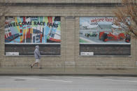 A man walks past signs for the Indianapolis 500, Wednesday, April 15, 2020, in Indianapolis. Indianapolis Motor Speedway, home of the Indianapolis 500, is closed due to the coronavirus pandemic. (AP Photo/Darron Cummings)