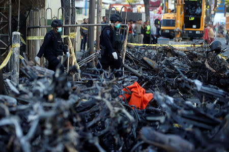 Members of the Indonesian Special Forces Police counter-terrorism squad walk by burned motorcycles following a blast at the Pentecost Church Central Surabaya (GPPS), in Surabaya, Indonesia May 13, 2018. REUTERS/Beawiharta