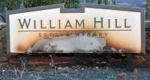 <p>The William Hill Estate winery sign is seen partially burnt in Napa, California on Oct., 9, 2017, as multiple wind-driven fires continue to whip through the region. (Photo: Josh Edelson/AFP/Getty Images) </p>