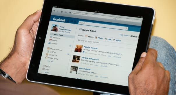 Close up view of a man using Facebook with iPad