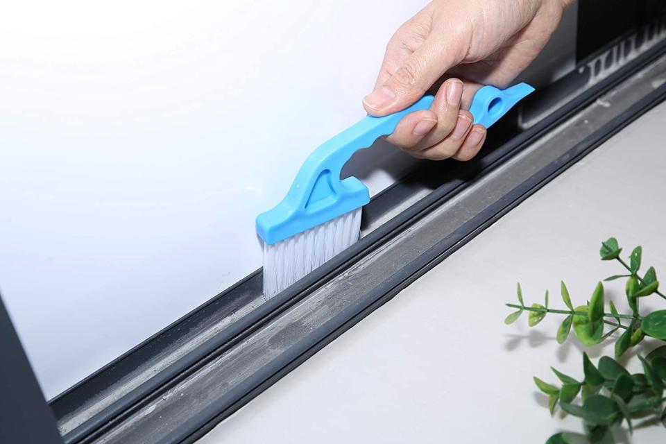 A model using the blue cleaning brush on a window