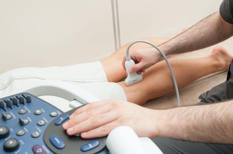 A doctor performs an ultrasound on a peron's legs to look for blood clots.