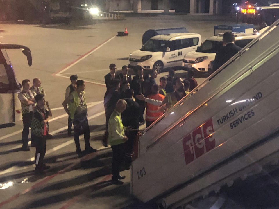 The scene observed by Associated Press photographer Hussein Malla as security, police and and officials remove a passenger from a Turkish Airlines jetliner after the passenger was subdued by passengers and crew following takeoff from Istanbul, Turkey, Friday June 14, 2019. The unidentified man began smashing at an oxygen mask box and damaged a cabin window, before pushing flight attendants aside and rushing toward the cockpit, but then he calmed down and after about 2½ hours flying, the pilots announced that the plane would return to Istanbul.(AP Photo/Hussein Malla)