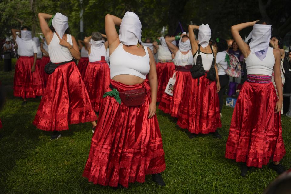 Women perform covering their faces with white scarves to symbolize that women are invisible in the justice system during an International Women's Day event in Lima, Peru, March 8, 2024. (AP Photo/Martin Mejia)